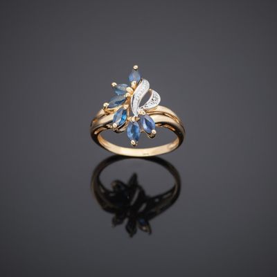 a gold ring with blue sapphires and diamonds on a black surface