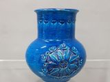 un vase bleu exposé sur une étagère transparente