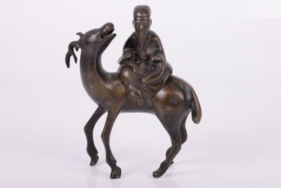 figurine en bronze représentant un homme à dos de chameau avec une chèvre