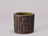 a close up of a brown and green cup on a white surface