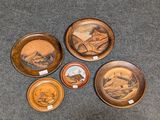quatre assiettes en bois ornées de motifs différents, posées sur un tapis