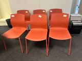 quatre chaises en plastique orange sont alignées en rangée