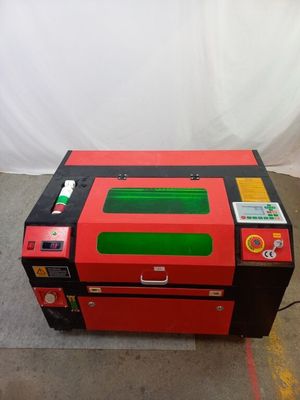 une machine laser rouge et noire posée sur un sol en béton