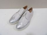 white leather shoes with silver laces on top of a white surface