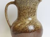 a brown and brown pitcher sitting on a white surface