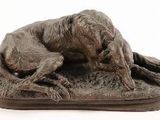 statue of a dog laying down on the ground on a white background