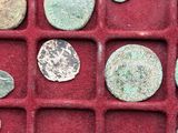 an assortment of ancient roman coins in a red box
