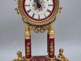 a red and gold clock sitting on top of a table