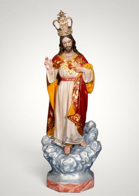 the statue of jesus is standing on a cloud with a crown on his head