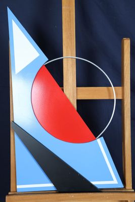 un tableau posé sur un chevalet, sur lequel figurent un cercle rouge et un triangle bleu