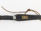 a knife with a leather sheath on it on a white surface