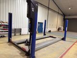 an image of a garage with a large lift in the middle of it