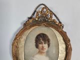 an old picture of a woman in a white dress is hanging on a wall