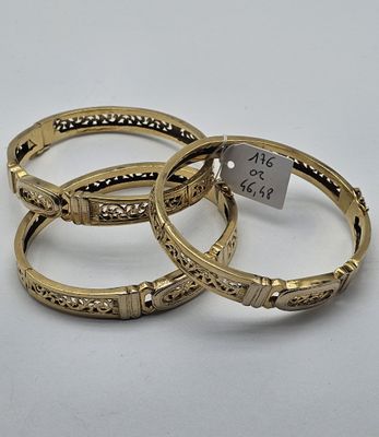 trois bracelets rigides en or ornés de motifs gravés et d'une étiquette de prix