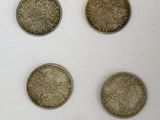 six pièces de monnaie britanniques différentes présentées dans une vitrine posée sur un support blanc