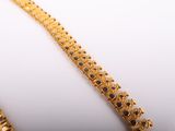 a close up of a gold bracelet on a white surface