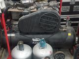 two air compressors sitting next to each other in a room