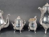 four pieces of silver tea and coffee set on a table