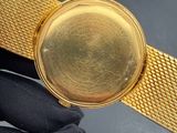 someone is holding a gold watch with a black glove on it