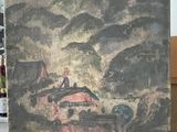 un vieux tableau représentant un village, posé sur une table devant une fenêtre
