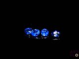 trois saphirs bleus sur une surface noire dans l'obscurité