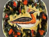a plate with a bird painted on it sitting on a table