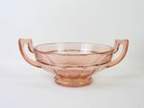 pink glass bowl with handles and handles on a white surface