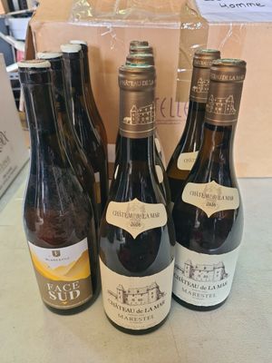 trois bouteilles de vin posées sur une table à côté d'un carton