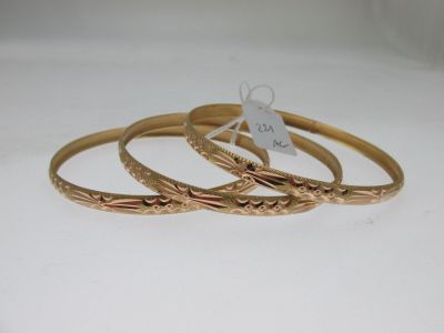 trois bracelets rigides en or sur fond blanc, avec une étiquette de prix