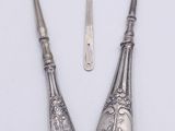 two silver spoons and a knife on a white surface