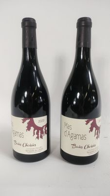 two bottles of red wine sitting next to each other on a white surface