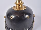 une cloche ancienne en laiton et noir, surmontée d'un capuchon doré