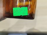 a person holding a brown bottle with a green sticker on it