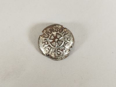 une pièce d'argent ornée d'une croix, posée sur une surface blanche