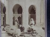 an old photo of a group of people sitting outside of a building