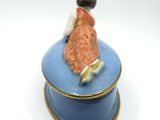 a small blue box with a figurine of a woman sitting on it