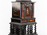 une horloge noire et dorée posée sur un socle, sur fond blanc