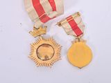 two medals on a white surface with a red and white ribbon
