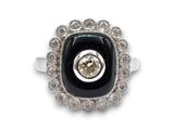 une image représentant une bague ornée d'une pierre noire entourée de diamants blancs