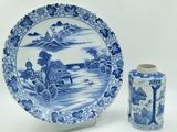 une assiette bleue et blanche et un vase posés sur une table