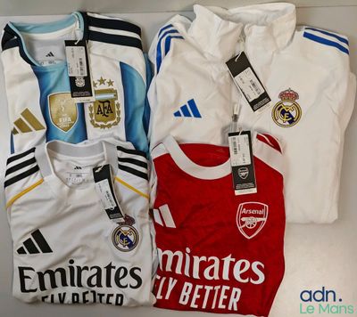 Trois maillots de football sont posés sur une table, avec leurs étiquettes encore attachées.