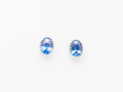 une paire de boucles d'oreilles en saphir bleu et diamants sur fond blanc
