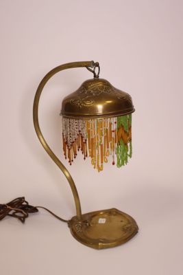 une photo d'une lampe de table surmontée d'un abat-jour orné de perles