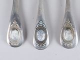 four silver spoons with a picture of a woman in a frame on them