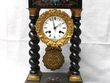 une horloge noire et dorée posée sur un socle, avec une clé