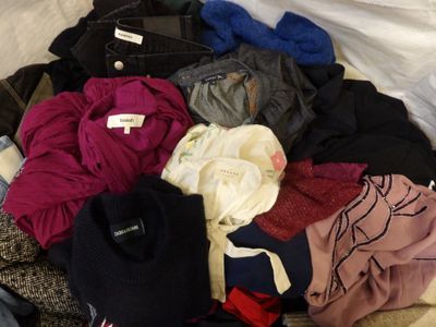 a pile of clothes on a bed with a white sheet