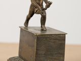 a small statue of a cupid holding a tennis racquet