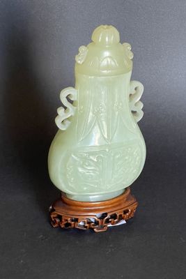 a green vase sitting on a wooden stand on a black surface