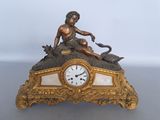 a gold clock with a statue of a woman sitting on top of it