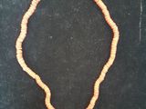 un collier de perles orange muni d'un fermoir en argent, posé sur un fond noir